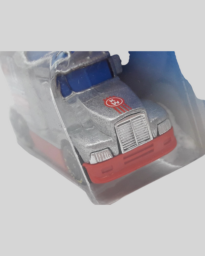 More Than Diecast Hot Wheels Ford LTL Kenworth T600 race truck in silver, blue, and red inside a protective case.