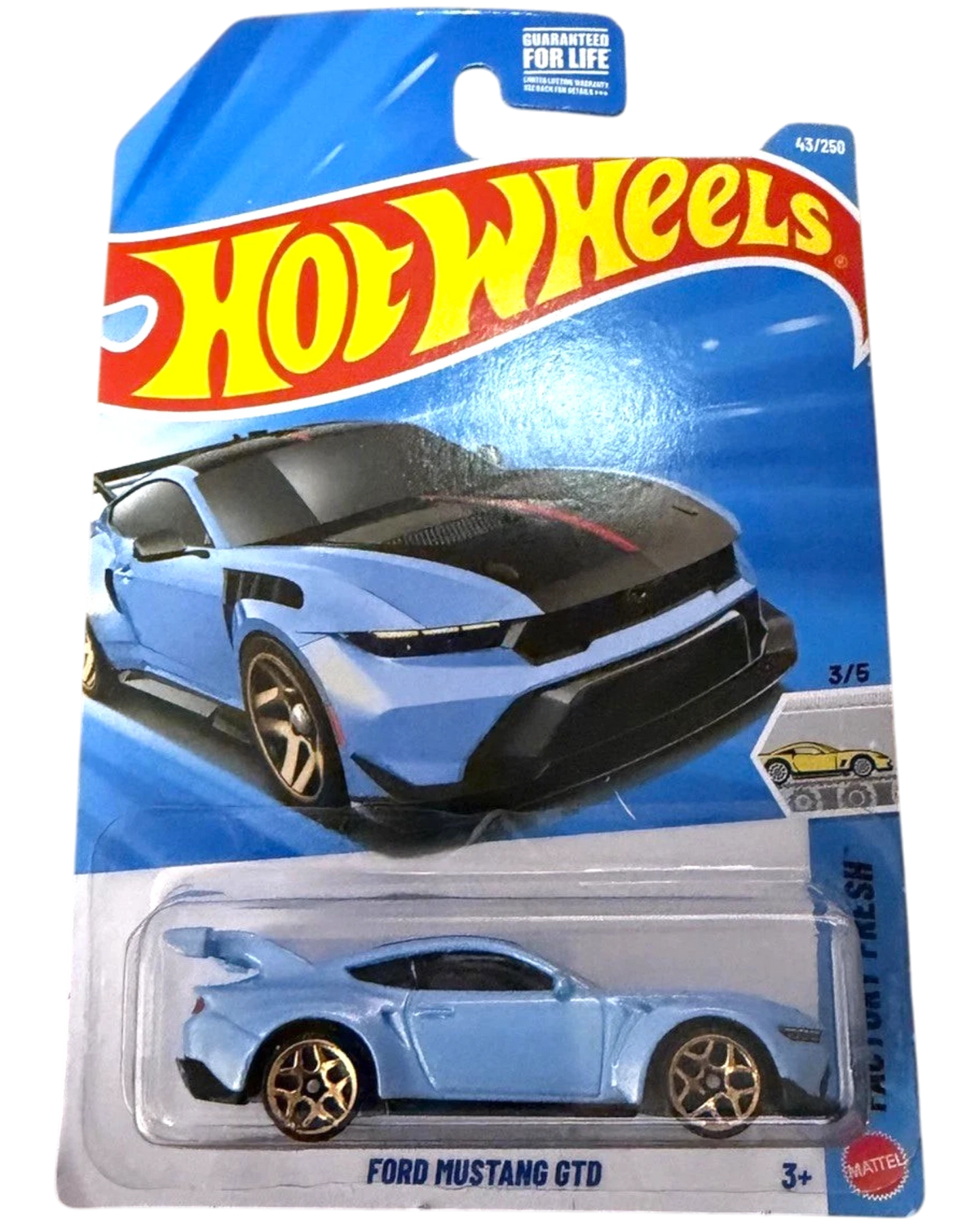 More Than Diecast Hot Wheels Ford Mustang GTD die-cast car in light blue with gold wheels and a large rear spoiler, displayed in its original packaging.