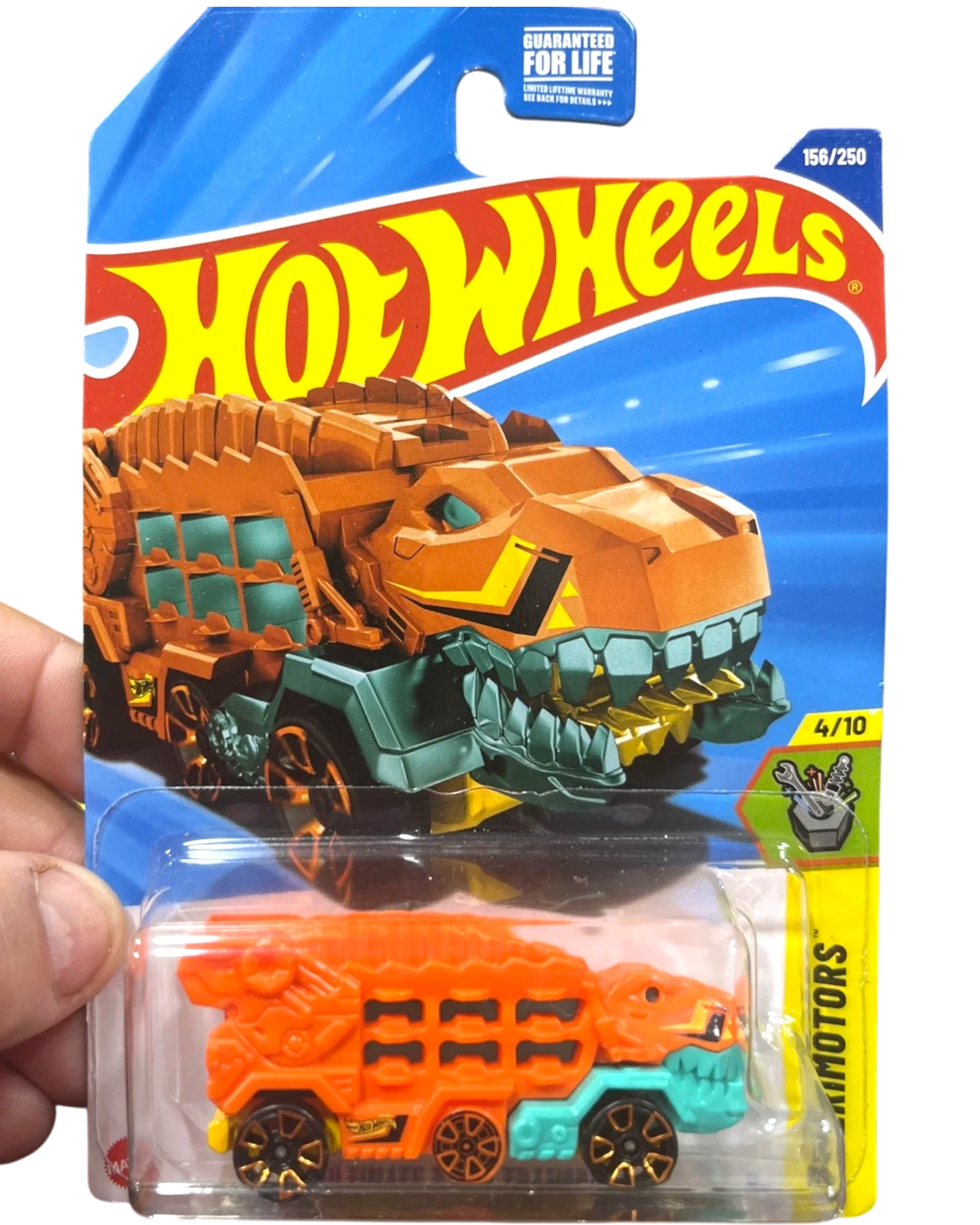 More Than Diecast Hot Wheels Experimotors T-Rex Transporter toy truck, orange with teal accents and gold wheels.