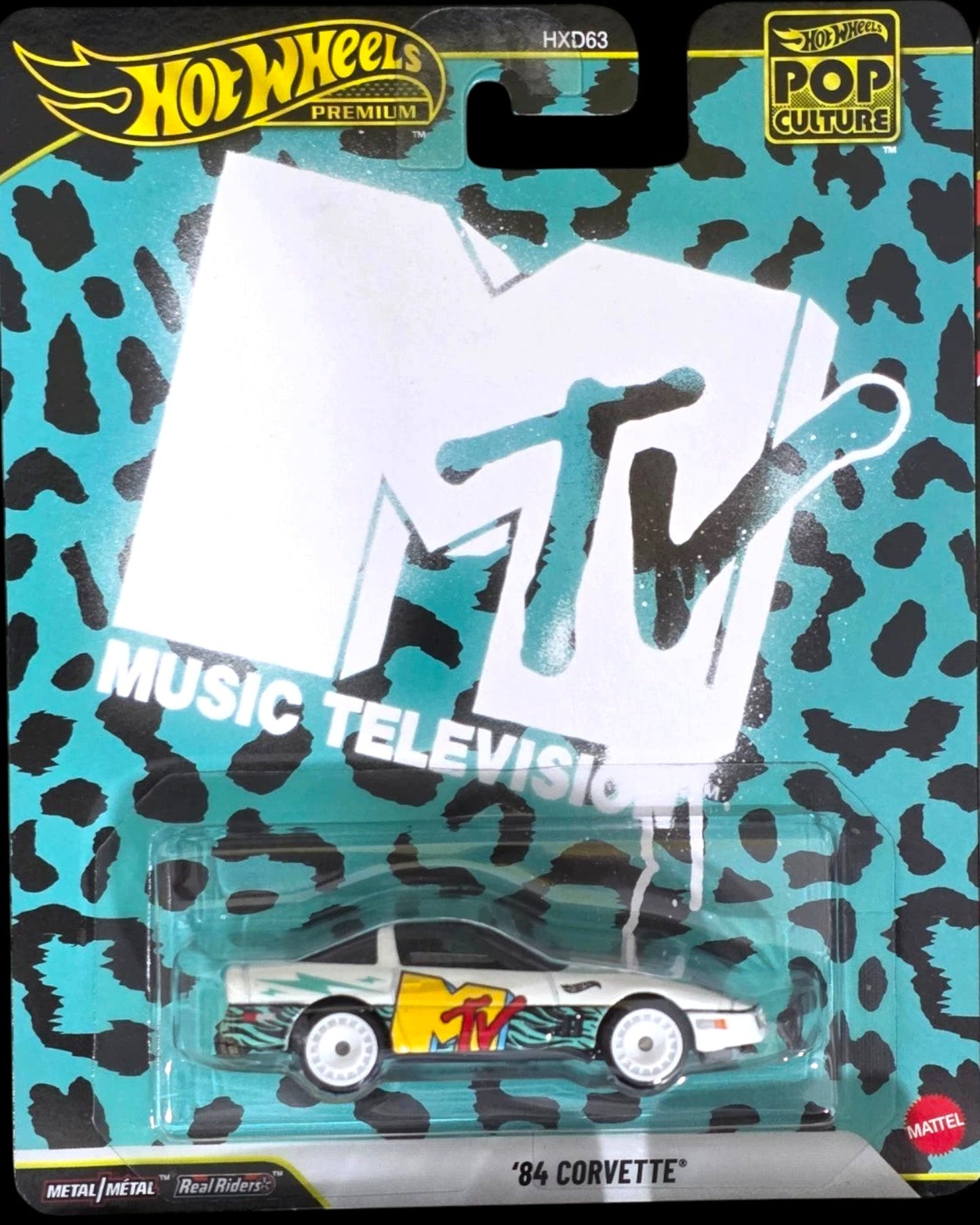 More Than Diecast Hot Wheels Premium Pop Culture MTV '84 Corvette die-cast car with white, yellow, and teal accents on a leopard print background.