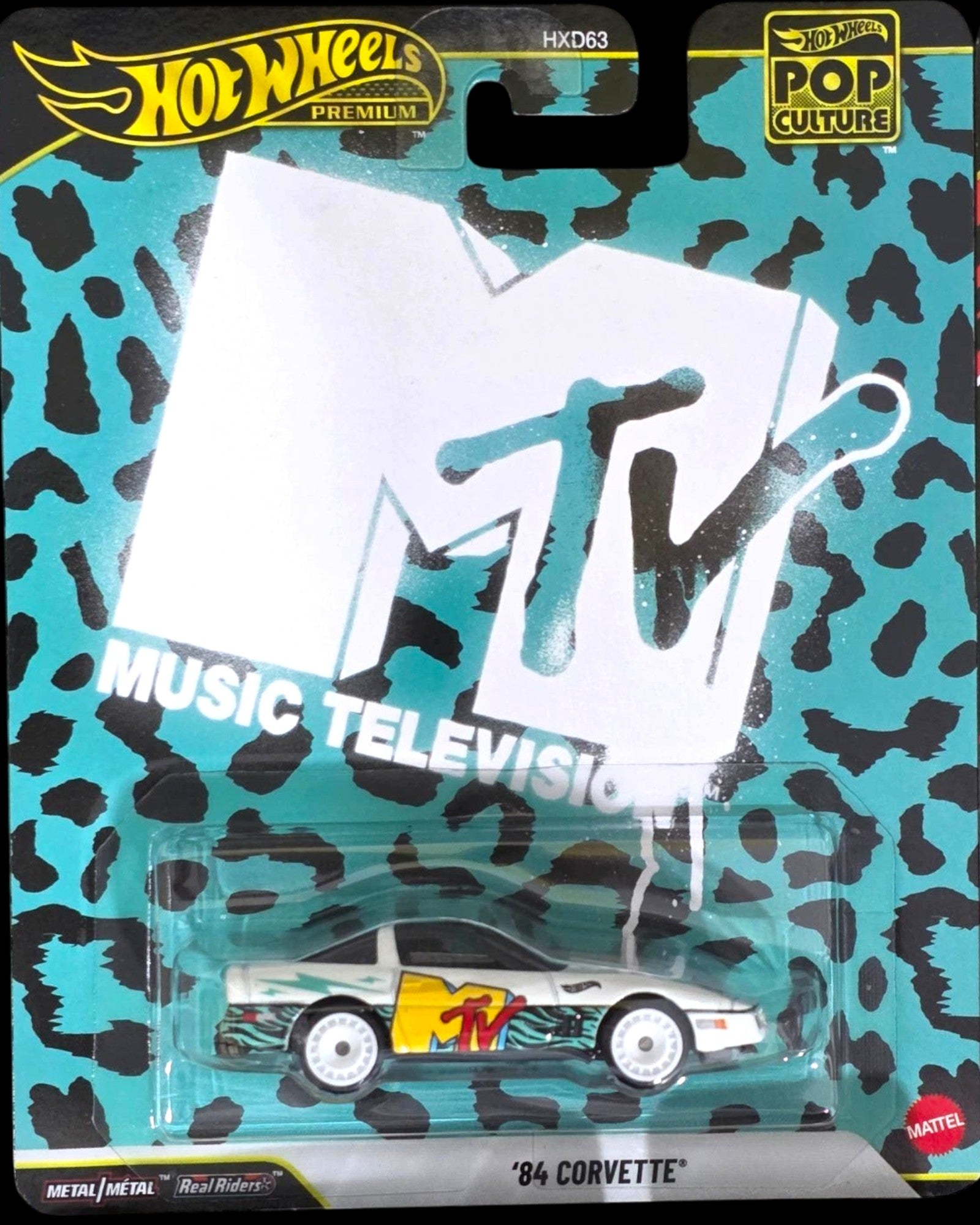 More Than Diecast Hot Wheels Premium Pop Culture MTV '84 Corvette die-cast car with white, yellow, and teal accents on a leopard print background.