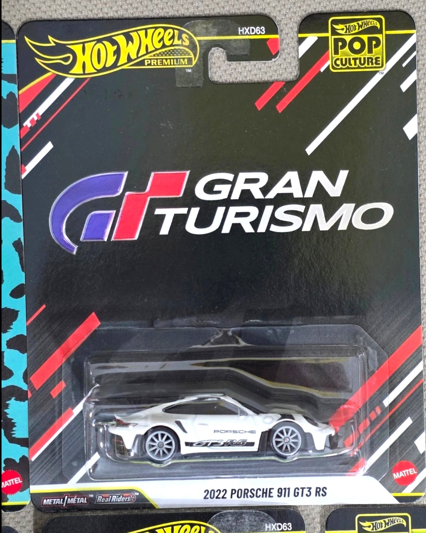 More Than Diecast Hot Wheels Pop Culture Gran Turismo 2022 Porsche 911 GT3 RS, white die-cast toy car with black accents and Real Riders wheels.